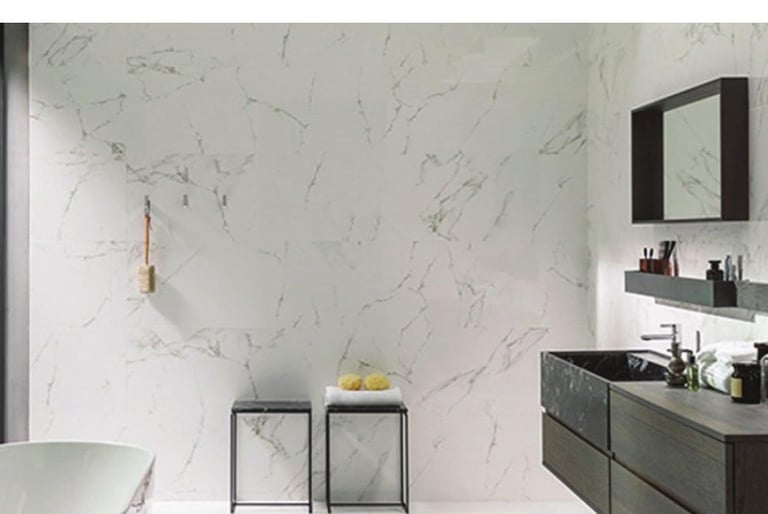 Modern bathroom with white marble walls, dark vanity with sink, mirror, and metallic pendant light fixtures